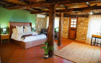 a bedroom with a bed and a stone wall at Silverlakes Farm Hotel in Pretoria