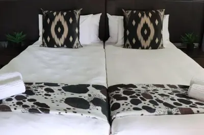 two beds with black and white sheets and pillows at Silverlakes Farm Hotel in Pretoria