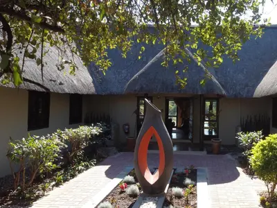 a statue in front of a house with a building at Kokobela Lodge in Phalaborwa