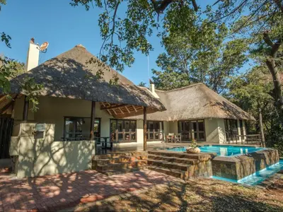 a house with a swimming pool in front of it at Kokobela Lodge in Phalaborwa