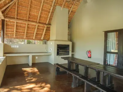 a living room with a table and a fireplace at Kokobela Lodge in Phalaborwa