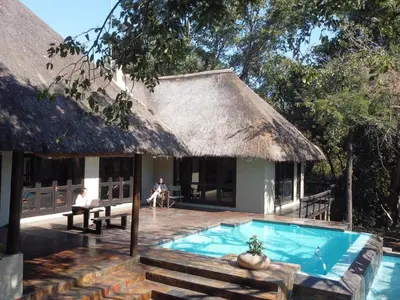a resort with a swimming pool and a hut at Kokobela Lodge in Phalaborwa