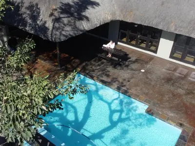 an overhead view of a person sitting on a bench next to a pool at Kokobela Lodge in Phalaborwa