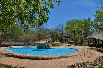 a swimming pool with a water fall in a park at Jackalberry Ridge by Dream Resorts in Marloth Park
