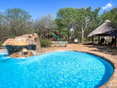 a swimming pool with a bench and a playground at Jackalberry Ridge by Dream Resorts in Marloth Park