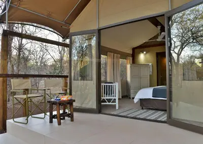 a room with a bedroom and a bed and windows at Jackalberry Ridge by Dream Resorts in Marloth Park