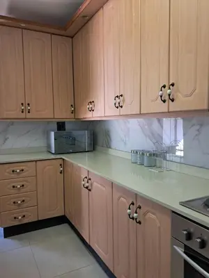 a kitchen with wooden cabinets and marble counter tops at Adam's Inn place in Hartbeespoort