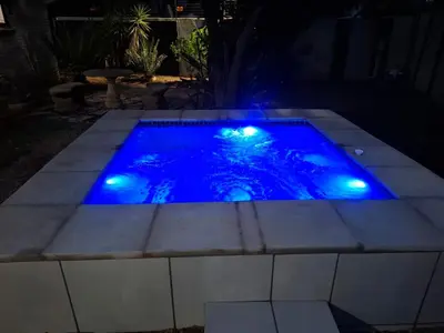 a pool with blue lights in a backyard at night at Adam's Inn place in Hartbeespoort