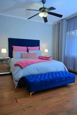 a bedroom with a large bed with a blue ottoman at Sublime Home in Bela-Bela