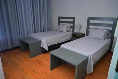 a room with two beds and a bench in it at Sublime Home in Bela-Bela