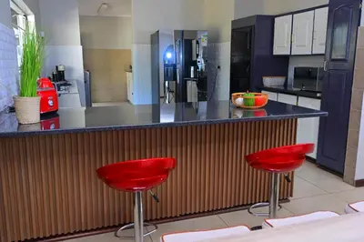 a kitchen with red bar stools at a counter at Sublime Home in Bela-Bela