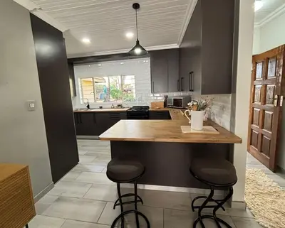 a kitchen with a island with two bar stools at Shamba Self-Catering in Pretoria
