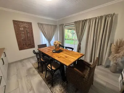 a dining room with a wooden table and chairs at Shamba Self-Catering in Pretoria