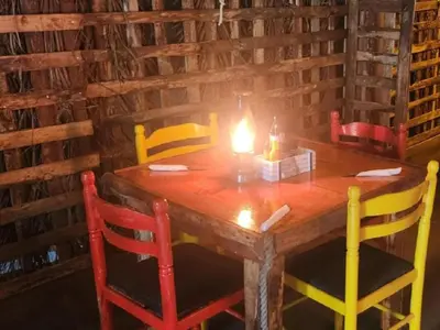 a wooden table with four chairs with a candle on it at Beach Island Graskop in Graskop