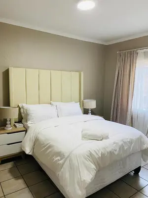 a bedroom with a large white bed and a window at Ekhaya Manor in Polokwane