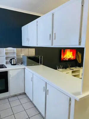 a kitchen with white cabinets and a fire in the wall at Ekhaya Manor in Polokwane