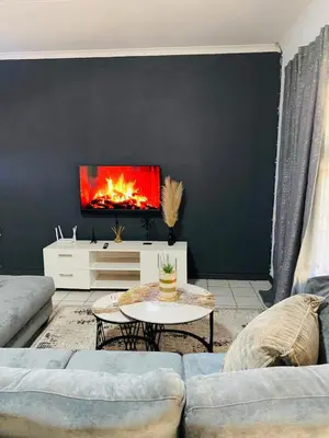 a living room with a couch and a fire on the wall at Ekhaya Manor in Polokwane