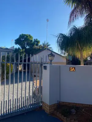 a white fence with a gate in front of a building at Ekhaya Manor in Polokwane