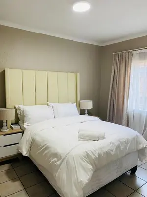 a bedroom with a large white bed and a window at Ekhaya Manor in Polokwane