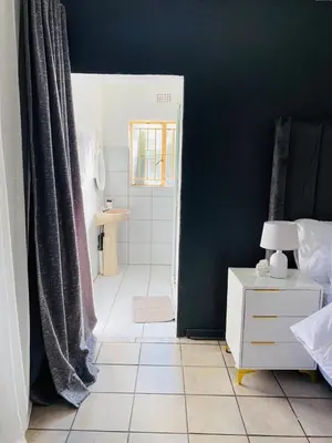 a bathroom with a shower and a white tiled floor at Ekhaya Manor in Polokwane