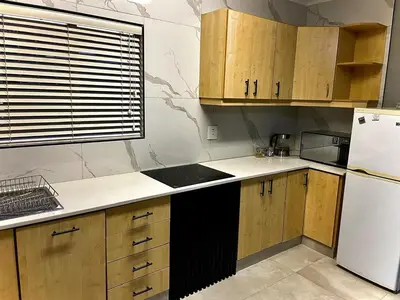 a kitchen with wooden cabinets and a white refrigerator at Little Swift 2 in Secunda