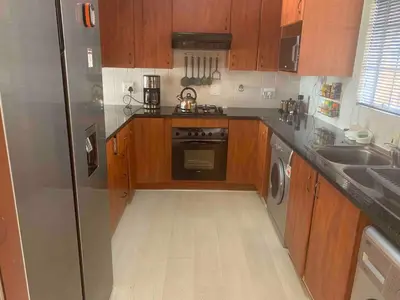 a kitchen with wooden cabinets and a stainless steel refrigerator at Imani's Retreat in Midrand