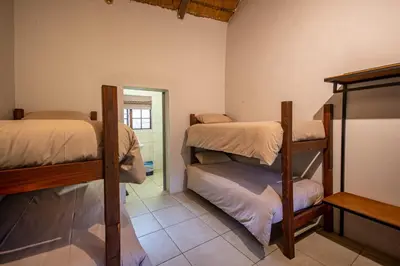 a room with three bunk beds and a doorway at Ons Plek Accommodation in Hazyview