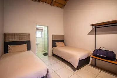 a bedroom with two beds and a suitcase in it at Ons Plek Accommodation in Hazyview