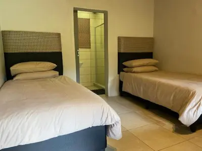 a bedroom with two beds and a walk in shower at Ons Plek Accommodation in Hazyview