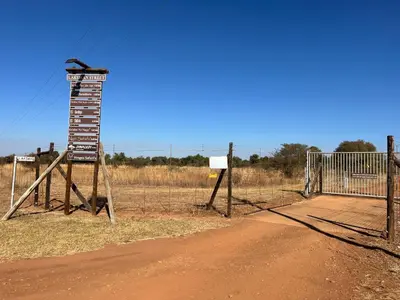 a fence with a sign next to a dirt road at Paradise & Private Padel Court in Dinokeng Game Reserve in Hammanskraal