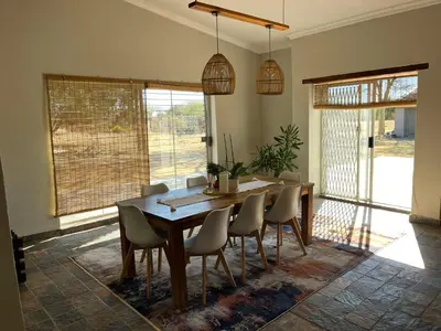 a dining room with a wooden table and chairs at Paradise & Private Padel Court in Dinokeng Game Reserve in Hammanskraal