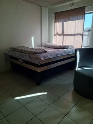 a bed in a room with a window and a chair at Patio Executive in Midrand