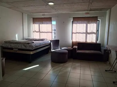 a room with a bed and a couch and a chair at Patio Executive in Midrand