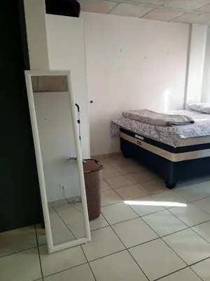 a bedroom with a bed and a mirror on a tiled floor at Patio Executive in Midrand