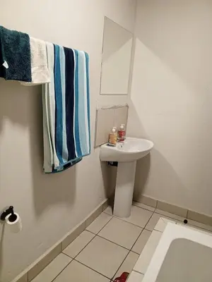 a white bathroom with a sink and a mirror at Patio Executive in Midrand