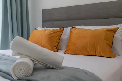 a bed with orange pillows and a towel on it at Menlyn Chique Apartment in Pretoria