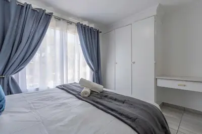 a bedroom with a bed with blue curtains at Menlyn Chique Apartment in Pretoria