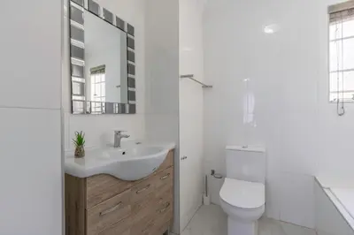 a white bathroom with a sink and a toilet at Menlyn Chique Apartment in Pretoria