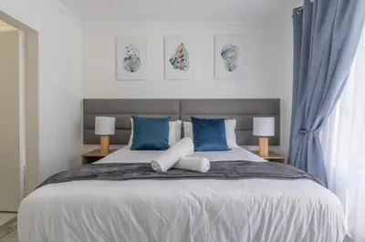 a bedroom with a large bed with blue and white pillows at Menlyn Chique Apartment in Pretoria