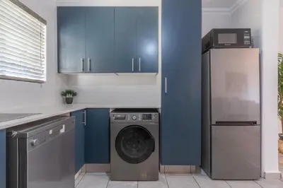 a kitchen with a washing machine and blue cabinets at Menlyn Chique Apartment in Pretoria