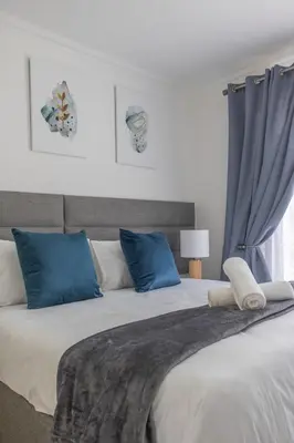 a bedroom with a large bed with blue pillows at Menlyn Chique Apartment in Pretoria
