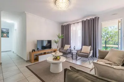 a living room with a couch and a tv at Menlyn Chique Apartment in Pretoria