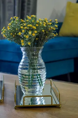 a glass vase with yellow flowers on a table at Midrand Cozy in Midrand