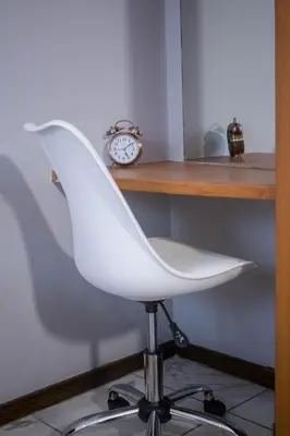 a white chair sitting next to a desk with a clock at Midrand Cozy in Midrand