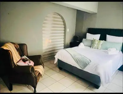 a bedroom with a bed and a chair at Rekganya Sunset Lodge in Phalaborwa