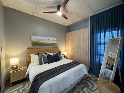a bedroom with a large bed with a ceiling fan at IBella's at The Urban in Pretoria