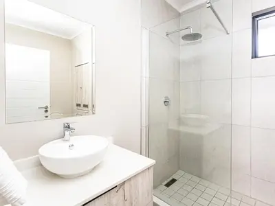a white bathroom with a sink and a shower at Thetan's Home Away From Home in Midrand