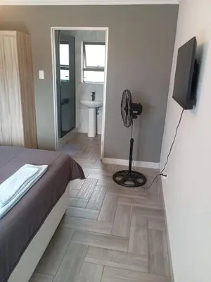 a bedroom with a bed and a television and a bathroom at Crystal Park Guest House in Benoni