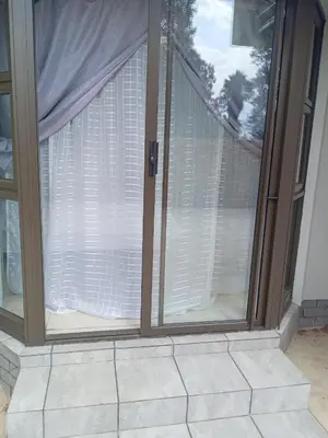 a sliding glass door with white curtains on it at Crystal Park Guest House in Benoni