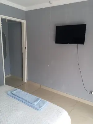 a bedroom with a flat screen tv on a wall at Crystal Park Guest House in Benoni